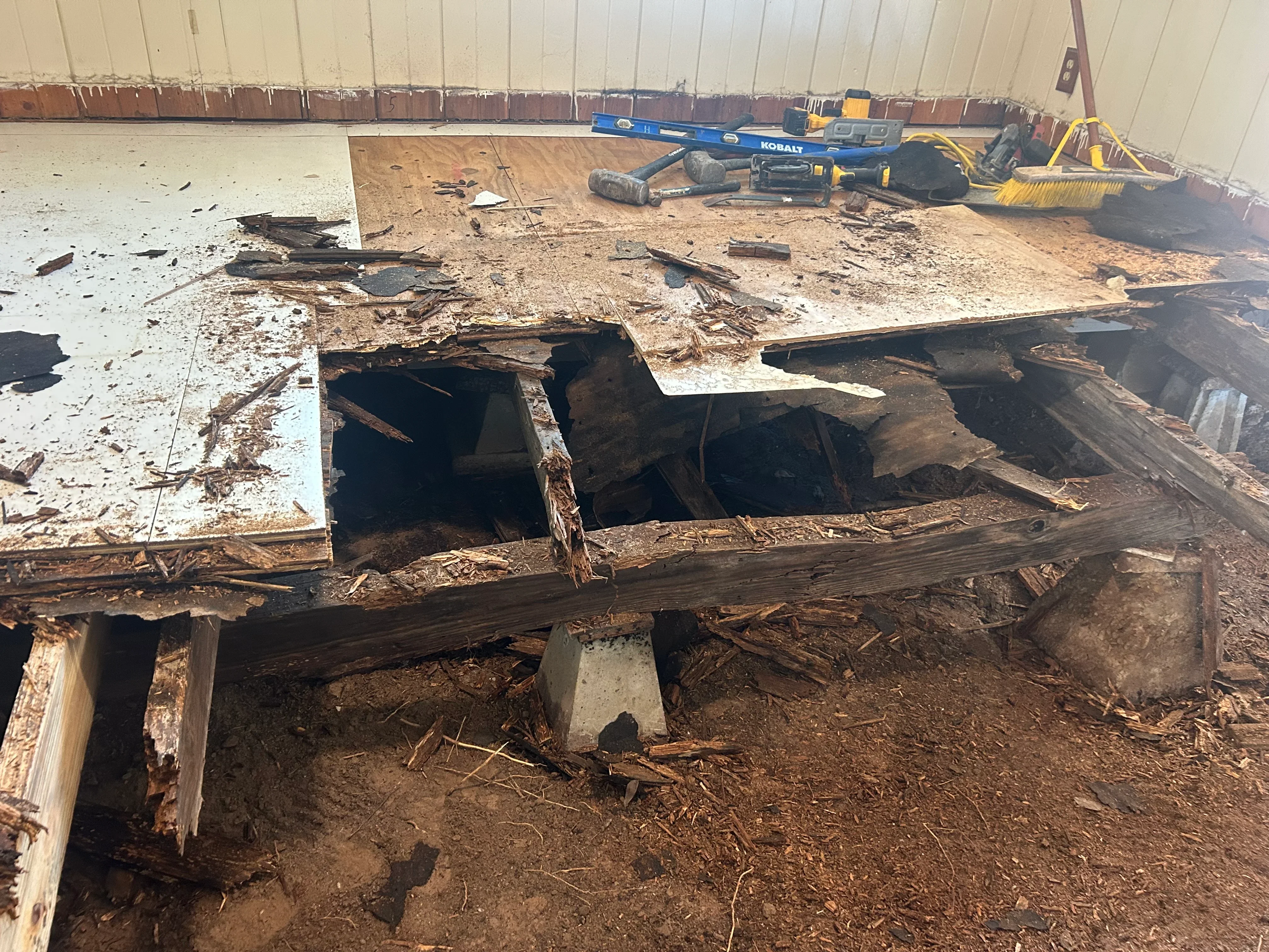 Exposed foundation pit showing removed wooden beams and concrete damage during repair work