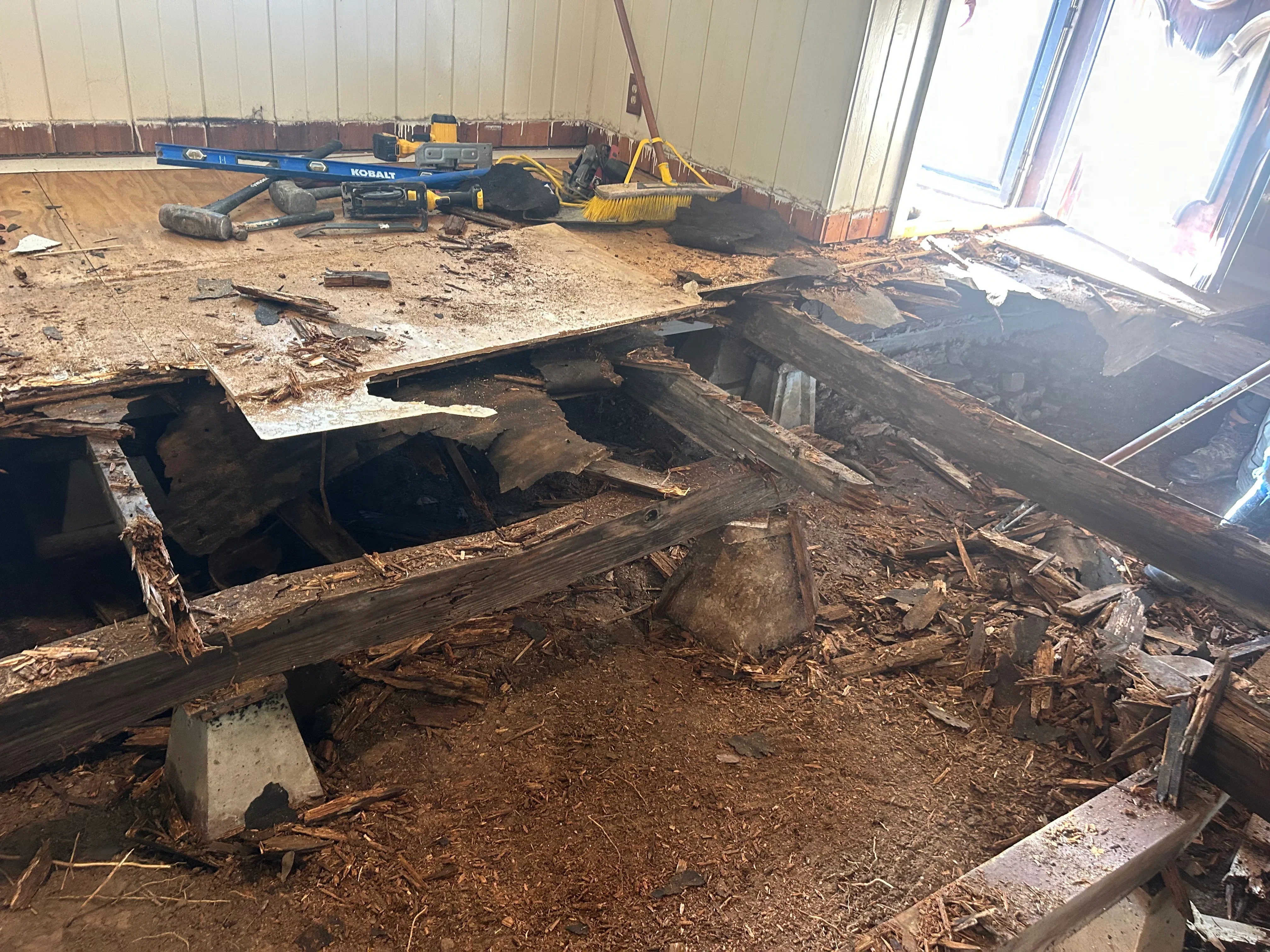 Exposed foundation with deteriorated wooden beams and structural damage requiring repair