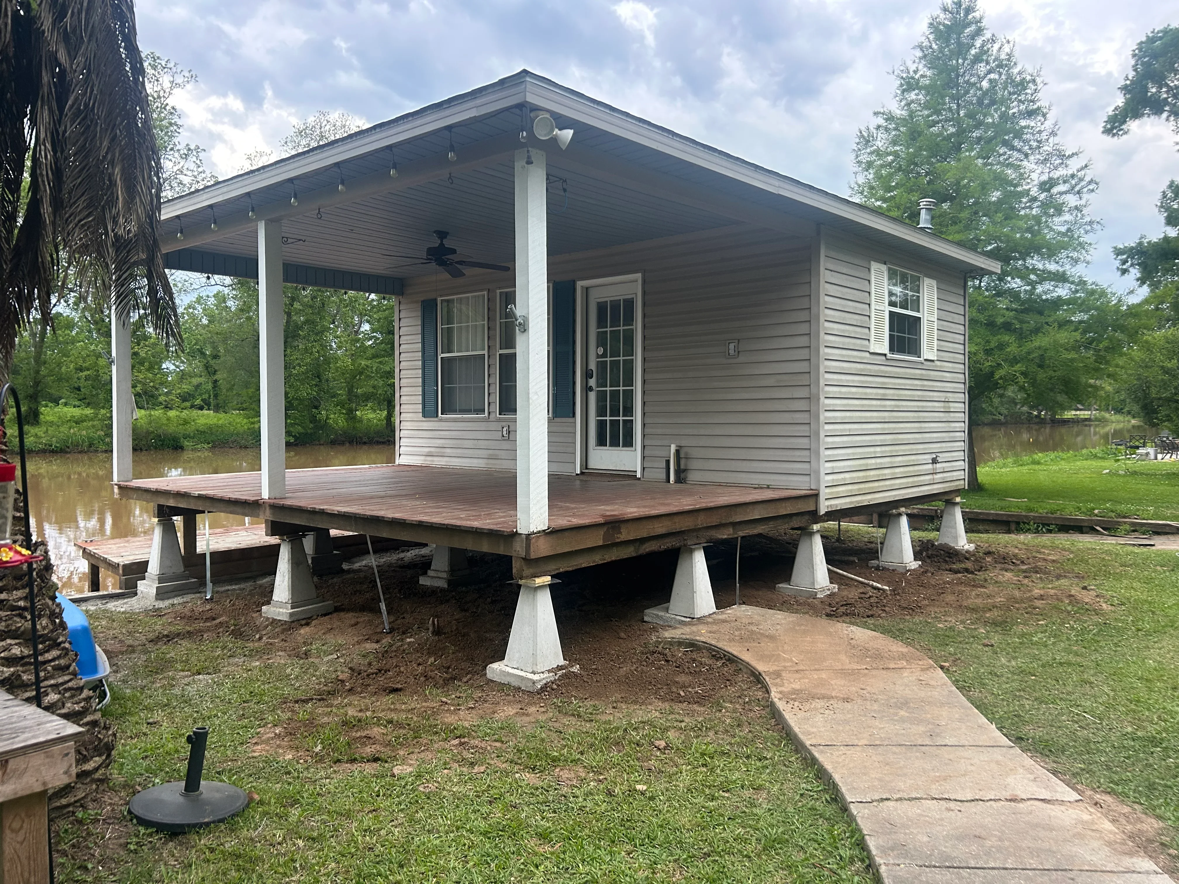 Elevated mobile home on concrete piers with new deck and covered porch in Lafayette